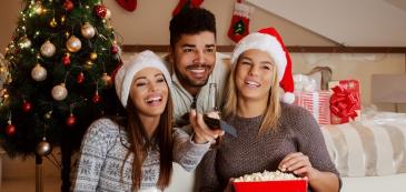 Zwei Frauen und ein Mann schauen Weihnachtsfilme