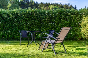 Gartentisch und -stühle im Garten vor Naturhecke